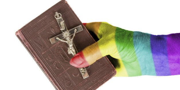 Hand (woman) holding a very old bible, isolated on white, rainbow flag