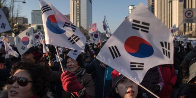 Pro-government activists shout slogans and wave flags as they stage a rally in central Seoul on February 25, 2017.South Korea's Constitutional Court will hold its final impeachment hearing to rule on the fate of President Park Geun-Hye at the end of the month, Yonhap News Agency reported February 22. / AFP / Ed JONES        (Photo credit should read ED JONES/AFP/Getty Images)