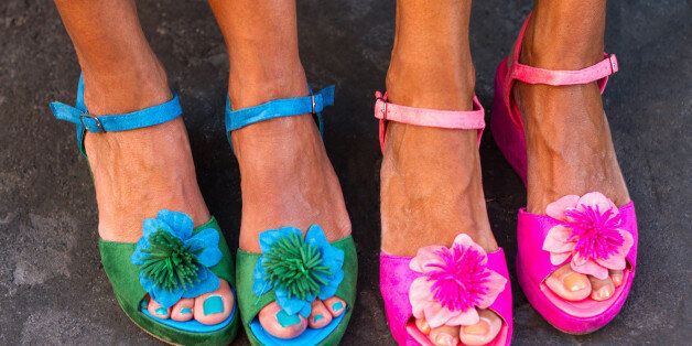 Four pretty pedicured feet in flowery sandals, side-by-side.