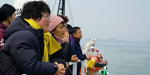 JINDO-GUN, SOUTH KOREA - MARCH 28: In this handout photo released by the South Korean Ministry of Oceans and Fisheries, Lee Geum-Hui (L), mother of Danwon High student Cho Eun-Hwa who went missing in the Sewol ferry looks at Sewol ferry as she stands on the deck of a boat on March 28, 2017 in Jindo-gun, South Korea. The Sewol sank off the Jindo Island in April 2014 leaving more than 300 people dead and nine of them still remain missing. Workers are in the process of an attempt to raise the ferry