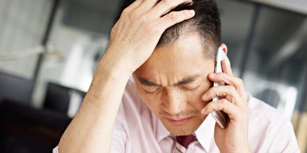 asian businessman talking on cellphone looking sad and frustrated.