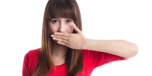 Beautiful young woman covering her mouth with her hand, isolated on white background