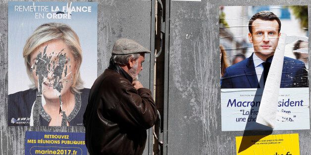 PARIS, FRANCE - APRIL 19:  A pedestrian walks past official campaign posters of Marine Le Pen, French National Front (FN) and political party leader and Emmanuel Macron, head of the political movement En Marche! (On move !), two of the eleven candidates who runs in the 2017 French presidential election on April 19, 2017 in Paris, France. Le Pen and Macron are candidates for the France's 2017 presidential elections and polls predict their presence in the second round of this election on May 07. (
