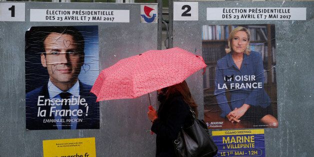 A woman walks past the new official posters for the candidates for the 2017 French presidential election, Emmanuel Macron, head of the political movement En Marche !, or Onwards !, (L) and Marine Le Pen, French National Front (FN) political party leader (R), in Paris, France, April 28, 2017. REUTERS/Gonzalo Fuentes