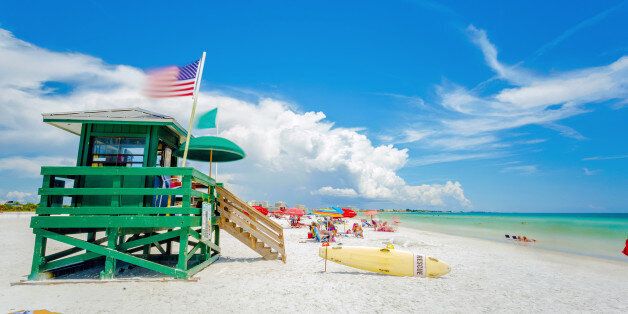 A lifeguard tower at an idyllic beach in a sunny summer day. Siesta Key beach at Sarasota, Florida, USA in the Gulf of Mexico. Emerald water and white sand with a national american flag in the wind.