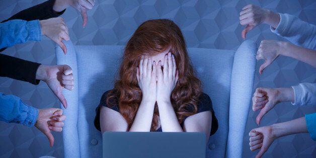 Girl with laptop covering face, around hands holding thumbs down