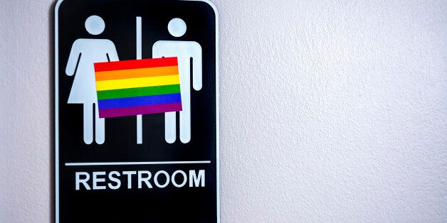 LGBT flag on a restroom sign posted on a wall. There is a lot of controversy over North Carolina's HB2 bill, the Carolina bathroom bill,  and other legislation around the US against the LGBT community.