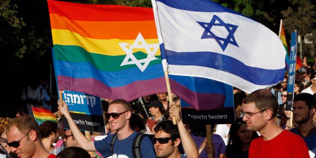 Participants hold flags during the gay pride parade in Jerusalem July 29, 2010. This year's parade marks the one-year anniversary of a shooting attack in a gay and lesbian youth center in Tel Aviv, in which two people were killed and 13 were injured. REUTERS/Ronen Zvulun (JERUSALEM - Tags: POLITICS SOCIETY)