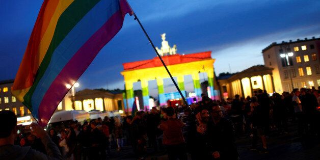 People stand in front of Brandenburg gate, lit up in support of the victims killed in an Orlando gay nightclub, in Berlin, Germany, June 18, 2016. REUTERS/Hannibal Hanschke