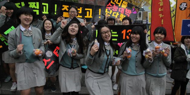 SEOUL, SOUTH KOREA - NOVEMBER 08:  South Korean high school girls cheer for their senior classmates taking the College Scholastic Ability Test on November 8, 2012 in Seoul, South Korea. More than 660,000 high school seniors and graduates sit for the examinations at 1,100 test centers across the country, where academic records are all important. Success in the exam, one of the most rigourous standardized tests in the world, enables students to study at Korea's top universities.  (Photo by Chung S