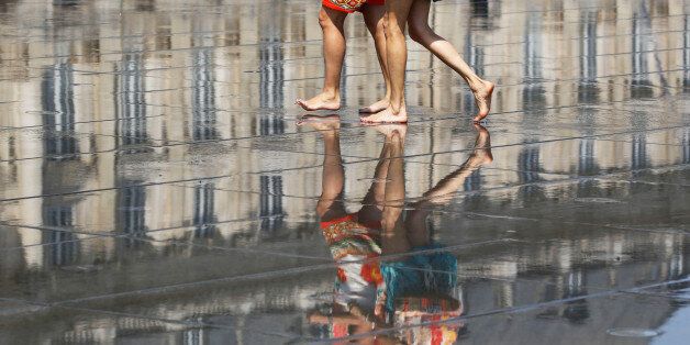 People cool off as they walk on a water mirror on the place de la Bourse in Bordeaux as hot summer temperatures hit France, June 22, 2017.  REUTERS/Regis Duvignau