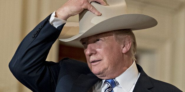 U.S. President Donald Trump puts on a Stetson cowboy hat while participating in a Made in America event, with companies from 50 states featuring their products, in the East Room of the White House in Washington, D.C., U.S., on Monday, July 17, 2017. Trump is seeking to highlight his economic agenda launching a series of theme weeks designed to highlight Trump's efforts to increase U.S. economic growth starting with Made in America week, during which the president plans to highlight companies tha