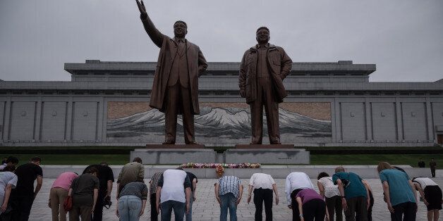 A group of tourists bow before statues of late North Korean leaders Kim Il-Sung (L) and Kim Jong-Il (R), on Mansu hill in Pyongyang on July 23, 2017.The Westerners lined up before giant statues of North Koreas founder Kim Il-Sung and his son and successor Kim Jong-Il on Sunday and, on command from their guide, bowed deeply - a ritual that the Trump administration intends to stop US tourists performing, with Washington due to impose a ban on its citizens holidaying in the Democratic People's Republic of Korea (DPRK), as the North is officially known. / AFP PHOTO / Ed JONES / TO GO WITH AFP STORY NKOREA-US-TOURISM-DIPLOMACY,FOCUS BY SEBASTIEN BERGER        (Photo credit should read ED JONES/AFP/Getty Images)