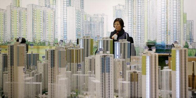 A visitor looks at a miniature model of an apartment complex which is currently under construction at its showroom in Seoul March 18, 2015. While activity is soaring, with the number of transactions at a 7-year high, housing prices are rising at a glacial pace as heavy household debt and a fast-ageing population keep a lid on price growth. To match story SOUTHKOREA-ECONOMY/HOUSING Picture taken on March 18. REUTERS/Kim Hong-Ji