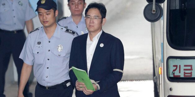 Jay Y. Lee, co-vice chairman of Samsung Electronics Co., right, is escorted by a prison officer as he arrives at the Seoul Central District Court in Seoul, South Korea, on Monday, Aug. 7, 2017. Lee last week rejected allegations that he paid bribes to a friend of South Koreas former president to secure support for a key merger. Photographer: Lee Young-ho/Pool via Bloomberg