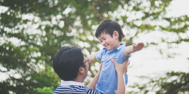 Asian father holding his son in the park