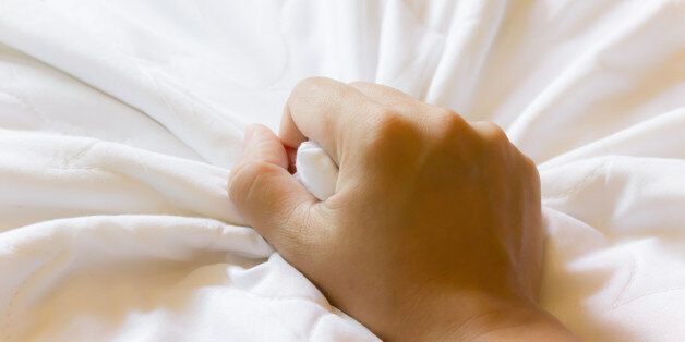 Hand grasp white bed sheet for good dreamy feeling in bed