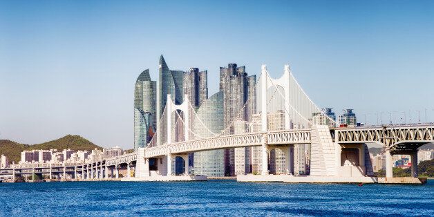 Panoramic view of the Gwangandaegyo Bridge in Busan, South Korea, with the ultra modern buildings of the Haeundae area in the background. Lit by late afternoon low sun.