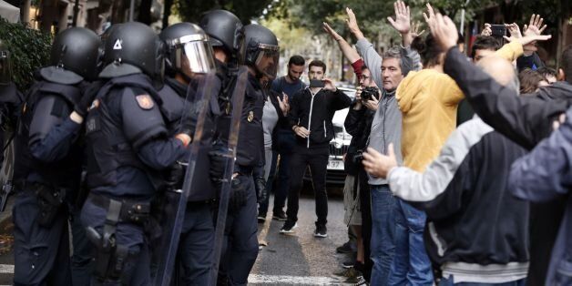 People raise their arms in front of Spanish police after the seizure of ballot boxes in a polling station in Barcelona, on October 1, 2017, on the day of a referendum on independence for Catalonia banned by Madrid.More than 5.3 million Catalans are called today to vote in a referendum on independence, surrounded by uncertainty over the intention of Spanish institutions to prevent this plebiscite banned by justice. / AFP PHOTO / PAU BARRENA        (Photo credit should read PAU BARRENA/AFP/Getty I