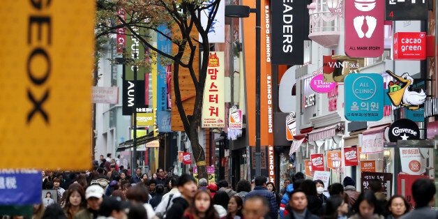 People walk past stores at the Myeongdong shopping district in Seoul, South Korea, on Monday, Oct. 31, 2016. As South Korean President Park Geun-hye's popularity plummets, members of her own party are publicly demanding action to staunch the bleeding from an influence-peddling scandal. Photographer: SeongJoon Cho/Bloomberg via Getty Images