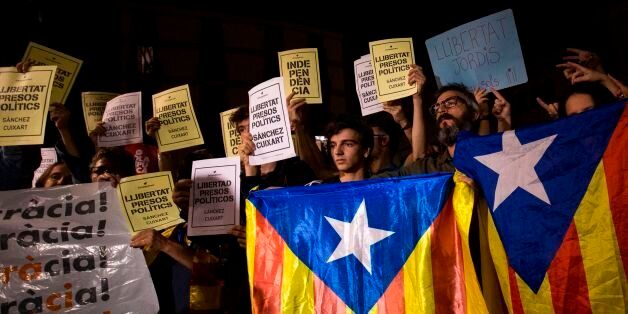 People hold Esteladas (Pro-independence Catalan flag) and papers reading in Catalan 'Freedom political prisoners' in front of the Generalitat Palace on October 17, 2017 in Barcelona.The demonstrators protested the judicial decision to imprison Spanish president of the Omnium Cultural, Jordi Cuixart, and Spanish president of the Catalan National Assembly (ANC), Jordi Sanchez. / AFP PHOTO / PAU BARRENA        (Photo credit should read PAU BARRENA/AFP/Getty Images)