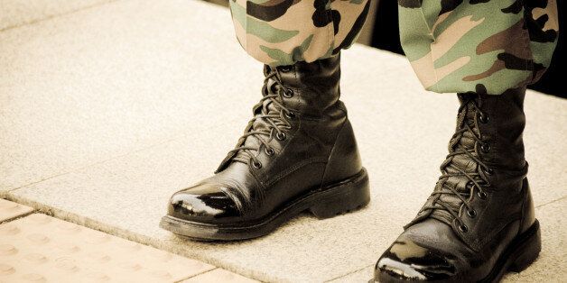 A solider in shiny boots stands at attention.