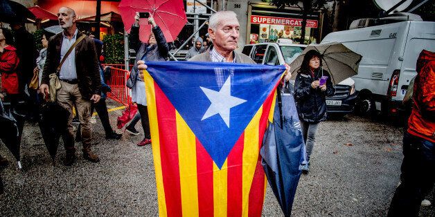 BARCELONA, CATALONIA, SPAIN - 2017/10/19: A man is seen while holding a flag of Catalonia front of the Government Delegation.Despite the heavy rains hundred of people gathered front of the Spanish Government Delegation in Barcelona to demand freedom for the two political prisoners Jordi Cuixart and Jordi SÃ nchez. This action falls within the days of demonstrations and actions that will take place during the next few weeks due to the application of article 155 that suspends the autonomy and th