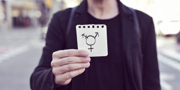 closeup of a young Caucasian man in the street showing a piece of paper with a transgender symbol drawn in it