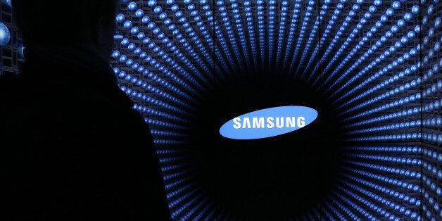 A visitor is silhouetted standing in front of the Samsung Electronics Co. logo displayed at the Semiconductor Rider experience at the company's d'light showroom in Seoul, South Korea, on Tuesday, Jan. 27, 2015. Samsung, the world's largest producer of smartphones using Google Inc.'s Android, is scheduled to release fourth-quarter earnings results on Jan. 29. Photographer: SeongJoon Cho/Bloomberg via Getty Images