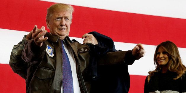 U.S. President Donald Trump puts on a U.S. Pacific Air Forces bomber jacket before delivering remarks to members of the U.S. military at Yokota Air Base, Japan November 5, 2017. REUTERS/Jonathan Ernst     TPX IMAGES OF THE DAY