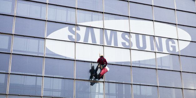 Paris, France - January 20, 2012: A window cleaner coming down from a tall skyscraper with the Samsung logo after the end of his work in the business district.