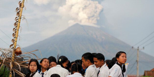 School children ride on the back of a truck on their way to school as Mount Agung volcano erupts in the background near Amed, Karangasem Regency, Bali, Indonesia November 28, 2017. REUTERS/Nyimas Laula