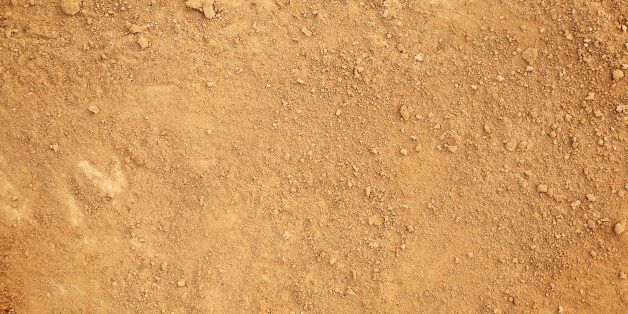 Photograph of tan colored dirt. Small clumps of dirt are sprinkled randomly over a layer of dry dirt and sand.