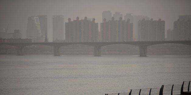 A man takes a selfie as he stands before the Han River and the Seoul city skyline during heavily polluted weather on February 23, 2015. The worst winter seasonal yellow dust in five years blanketed the Korean Peninsula, prompting the authorities to issue health warnings against the sandy, chemical-laden wind from China, according to domestic media. On a scale based on the US environmental Protection Agency standard, levels of fine particulate matter of ten micrometers or less (PM10) exceeded the