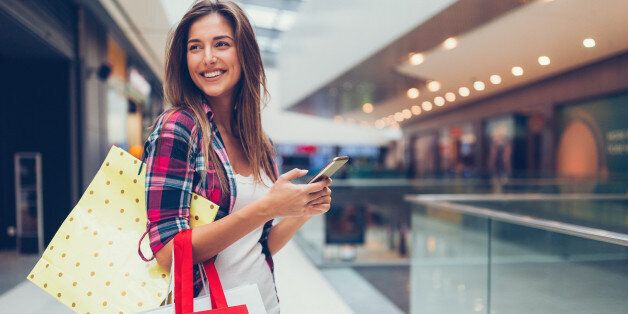 Happy girl with shopping bags texting on smartphone