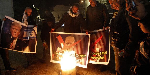 Palestinian protesters burn pictures of US President Donald Trump at the manger square in Bethlehem on December 5, 2017.   US President Donald Trump told Palestinian leader Mahmud Abbas in a phone call that he intends to move the US embassy from Tel Aviv to Jerusalem, Abbas's office said. / AFP PHOTO / Musa AL SHAER        (Photo credit should read MUSA AL SHAER/AFP/Getty Images)