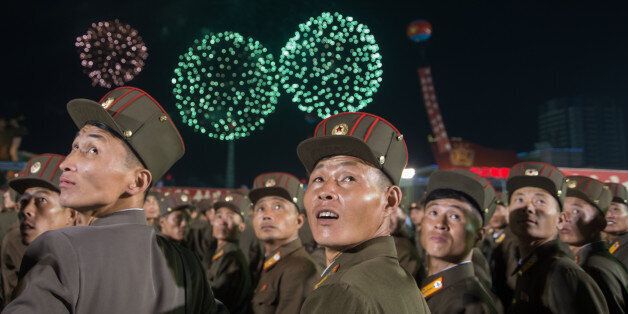 TOPSHOT - In a photo taken on September 6, 2017, Korean People's Army (KPA) soldiers cheer while watching fireworks during a mass celebration in Pyongyang for scientists involved in carrying out North Korea's largest nuclear blast to date.Citizens of the capital lined the streets September 6 to wave pink and purple pom-poms and cheer a convoy of buses carrying the specialists into the city, and toss confetti over them as they walked into Kim Il-Sung Square. / AFP PHOTO / Kim Won-Jin        (Phot