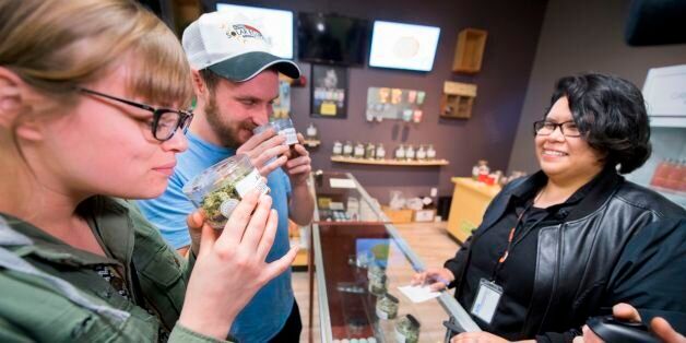 Tourists Laura Torgerson and Ryan Sheehan, visiting from Arizona, smell cannabis buds at the Green Pearl Organics dispensary on the first day of legal recreational marijuana sales in California, January 1, 2018 in Desert Hot Springs, California. / AFP PHOTO / Robyn Beck        (Photo credit should read ROBYN BECK/AFP/Getty Images)
