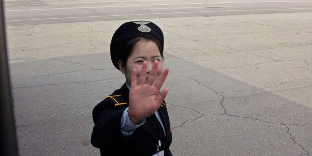 A ground staff of North Korean airliner Air Koryo thrusts a hand in front of her face at the airport in North Korean capital of Pyongyang October 12, 2010. REUTERS/Petar Kujundzic  (NORTH KOREA - Tags: POLITICS TRANSPORT)