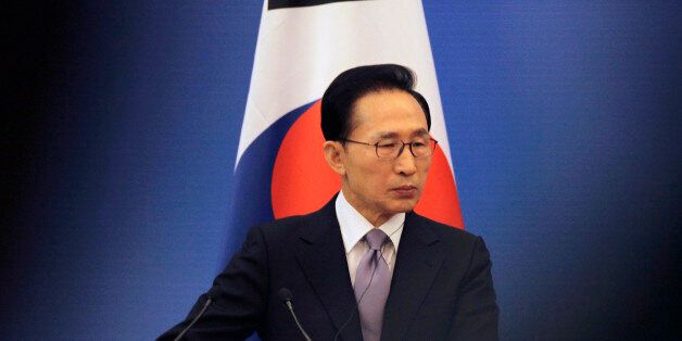 South Korea's President Lee Myung-bak stands in front of a South Korean national flag as he attends a joint news conference of the fifth trilateral summit among China, South Korea and Japan at the Great Hall of the People in Beijing, May 13, 2012. REUTERS/Petar Kujundzic (CHINA - Tags: POLITICS BUSINESS)