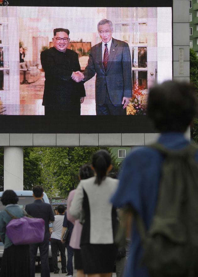 11일 평양 시내 스크린을 통해 방송된 김정은 국무위원장의 싱가포르 방문 관련 뉴스를 지켜보고 있는 주민들의 모습. 