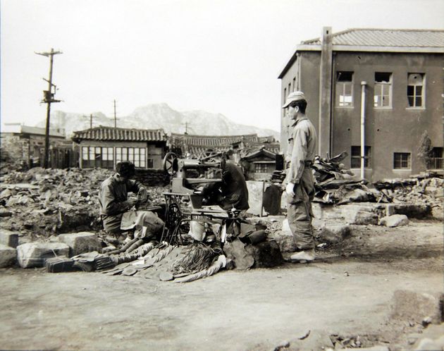 1950년 10월 28일 서울 수복 후, 한 수선공이 자기 가게가 있던 자리에서 다시 영업을 하며 전투화를 수선하는 모습. 
