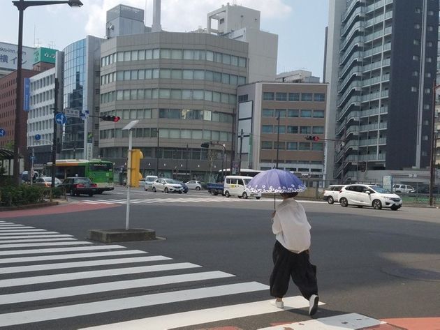 24일 일본 도쿄 주오구 거리에서 한 여성이 양산을 들고 횡단보도를 건너고 있다.