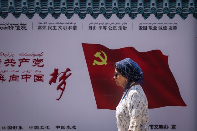 중국 신장위구르자치구 우루무치에서 한 위구르인이 중국 공산당 깃발이 새겨진 벽 앞을 지나고 있다. 2017년 6월27일.