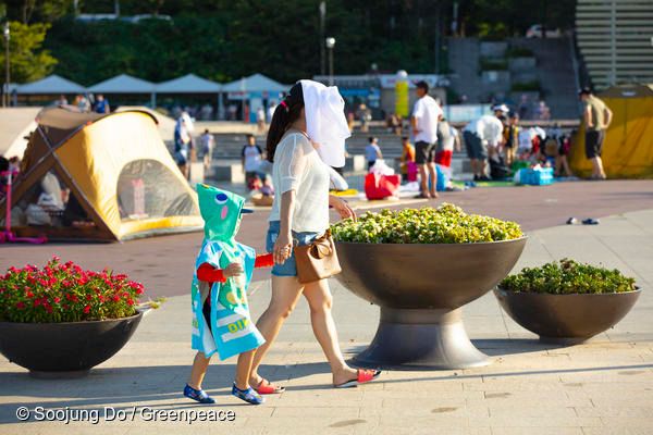 지난 11일 서울에서 어른과 아이가 열기를 피하기 위해 얼굴을 가린 채 걷고 있다