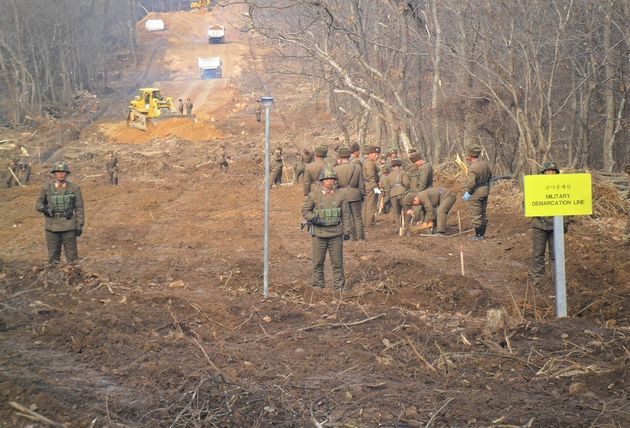 남북 군인들이 22일 중부전선 군사분계선 근처에서 만나 도로연결작업을 하고 있다.