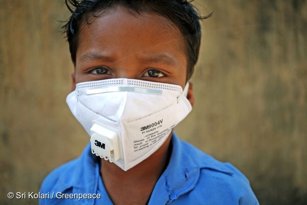 인도 차티스가르주의 한 남자 아이가 근처 석탄 발전소에서 날아오는 석탄재를 피하기 위해 마스크를 쓰고 있다