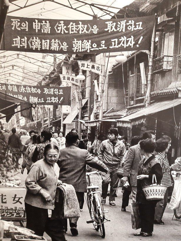 조지현 작가가 찍은 60년대말 오사카 이카이노의 조선 시장 풍경. 영주권을 죽음의 신청이라고 비난하며 한국적을 조선으로 고치자는 총련의 플랭카드가 붙어있다.