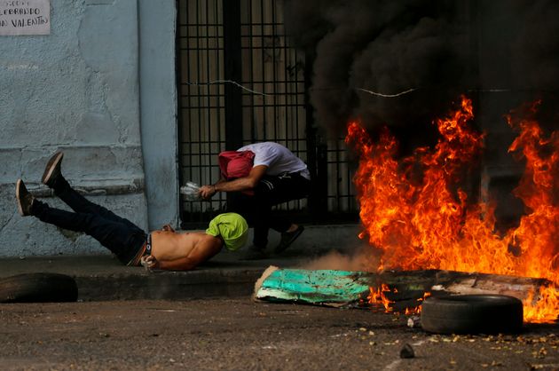 A demonstrator, left, falls after getting caught in a strand of barbed wire during clashes with the Bolivarian National Guard in Urena, Venezuela, near the border with Colombia, Saturday, Feb. 23, 2019. Venezuela's National Guard fired tear gas on residents clearing a barricaded border bridge between Venezuela and Colombia on Saturday, heightening tensions over blocked humanitarian aid that opposition leader Juan Guaido has vowed to bring into the country over objections from President Nicolas Maduro.(AP 