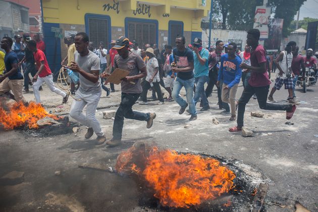 아이티 시위자들이 6월 9일 포르토프랭스에서 조베넬 모이즈(Jovenel Moïse) 대통령 퇴진을 요구하는 시위 중 불에 타고 있는 타이어 옆을 뛰어가고 있다.